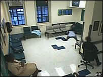 женщина упала со стула и лежит на полу лицом вниз в психиатрической больнице в Бруклине, окружающие не обращают на нее внимания (съёмка камеры наблюдения)