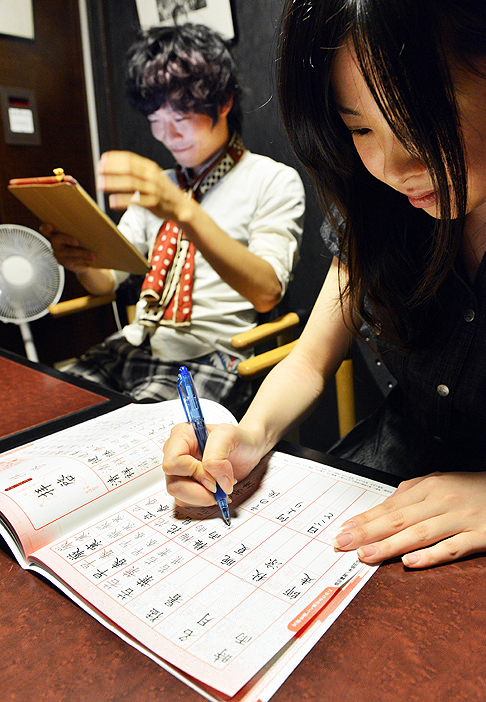 Акихиро Мацумура (слева) использует планшет, пока его друг практикуется в написании китайских иероглифов