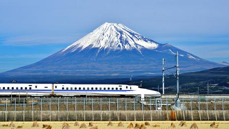 сверхскоростной пассажирский экспресс мчится мимо величественной горы Фудзияма в Японии
