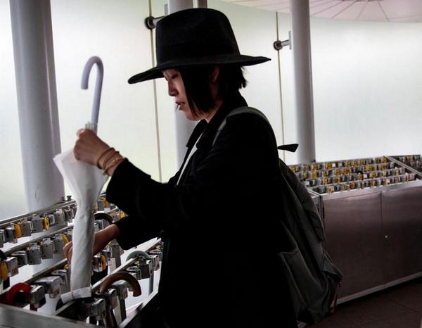 японка запирает зонт на замок в Национальном художественном центре Токио