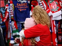 женщина и девочка на фоне привязанных к ограде фанатских шарфов в Ливерпуле
