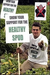 член Британского картофельного совета с плакатом Поддержи здоровый корнеплод!